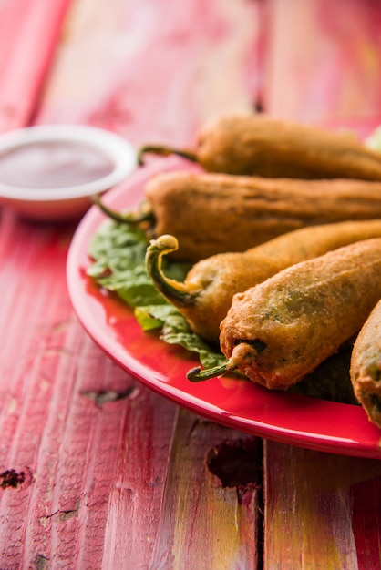 Chrupiące zielone Chilli Pakora lub Mirchi Bajji, podawane z ketchupem na nastrojowym tle. Jest to popularna przekąska na herbatę z Indii, szczególnie w Monsoon. Selektywne skupienie