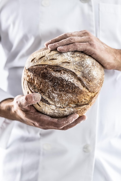Chrupiący bochenek świeżego chleba w rękach piekarza