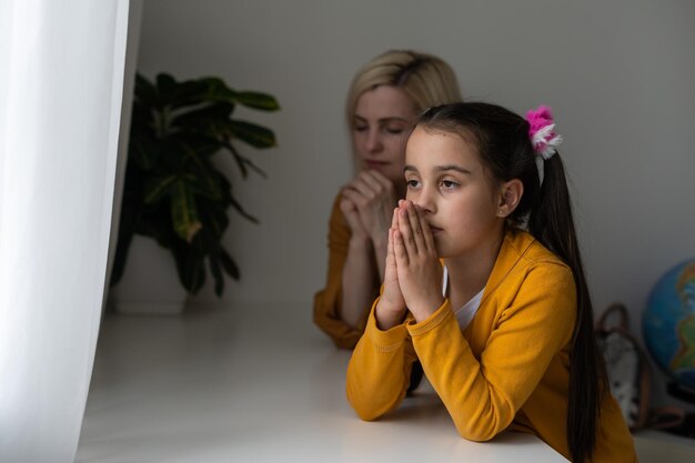 Chrześcijańska dziewczyna i jej matka modlą się w domu.