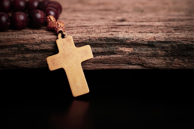 Chrześcijański drewniany krucyfiks z drewnianym różańcem na otwartej Biblii, obraz koncepcji religijnej,
