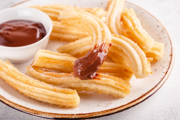 Churros z cukrem pudrem i sosem czekoladowym.