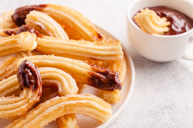 Churros z cukrem pudrem i sosem czekoladowym.