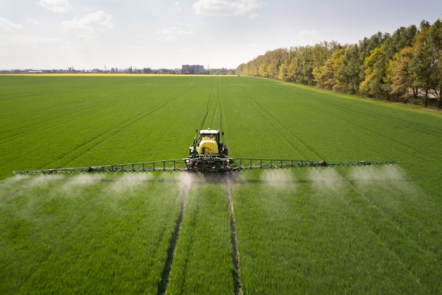 Ciągnik oprysku pestycydami opryskiwaczem na dużym zielonym polu rolniczym