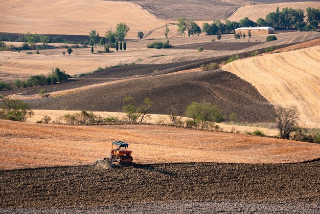 Ciągnik pracujący na terenach rolniczych krajobraz wsi w Toskanii we Włoszech