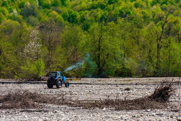 Ciągnik w suchym korycie rzeki w pobliżu górskiego lasu