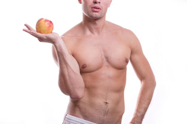 Ciało młodego, wysportowanego mężczyzny rasy kaukaskiej, nagie do pasa, na białym tle na białym tle z jabłkiem w dłoni