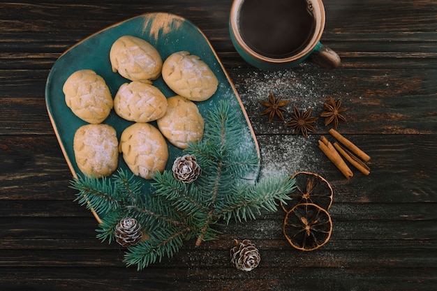 Ciasteczka jak szyszki na talerzu brzozowym z gałązką świerku i filiżanką kawy na drewnianym stole.