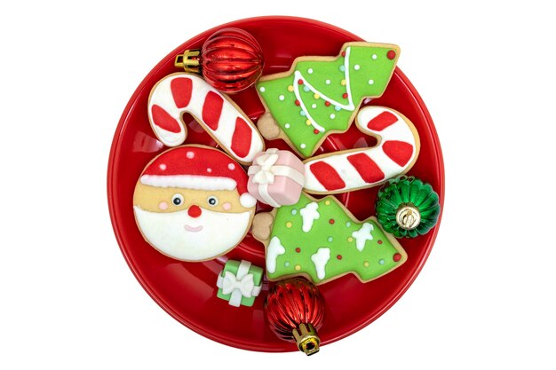 Ciasteczka powlekane cukrem na jasnoczerwonym talerzu z dekoracjami świątecznymi.