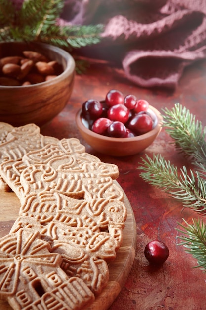 Ciasteczka świąteczne Speculoos lub Spekulatius z migdałami jagodowymi żurawiny na stole z ręcznikiem kuchennym i gałązkami jodły Tradycyjne niemieckie słodycze i ciasteczka na Boże Narodzenie lub Adwent
