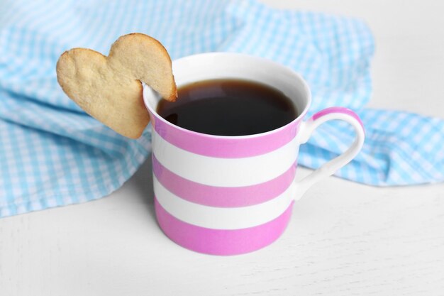 Ciastko w kształcie serca na filiżance kawy na stole zbliżenie