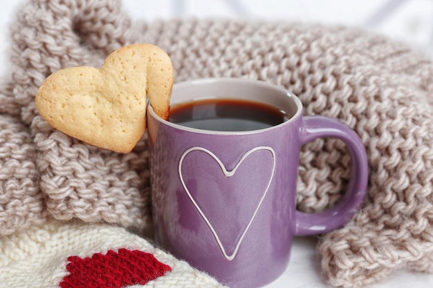 Ciastko w kształcie serca na filiżance kawy z zbliżeniem z dzianiny
