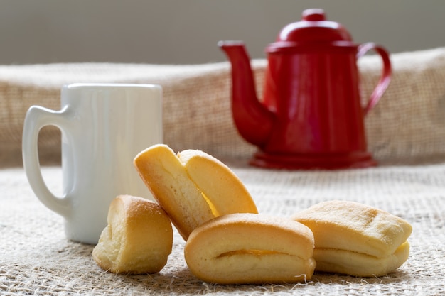 Ciastko z mąki pszennej, znane jako cangalhinha, używane w dolinie Paraíba do Sul do kawy w domach festiwalu Divino. biały kubek i czerwony imbryk.