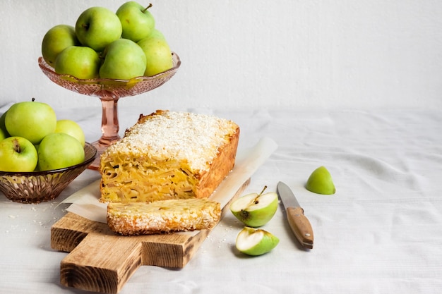 Ciasto bochenek jabłkowo-kokosowy i jabłka w wazonie na stole. Skopiuj miejsce