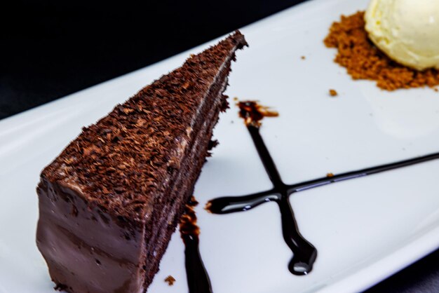 Zdjęcie ciasto czekoladowe na białym talerzu z lodami na czarnym tle