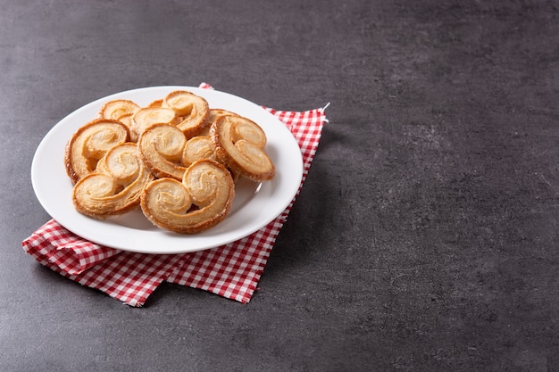 Ciasto francuskie Palmier w talerzu na czarnym tle łupków