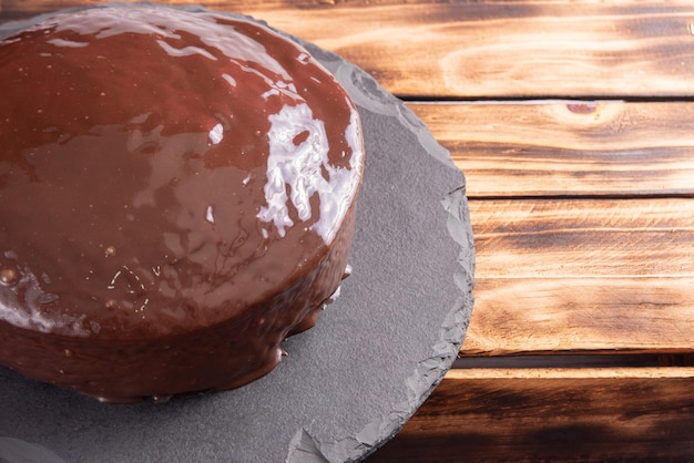 Ciasto marchewkowe pokryte czekoladą na kamiennej powierzchni nad rustykalnym drewnem selektywnym