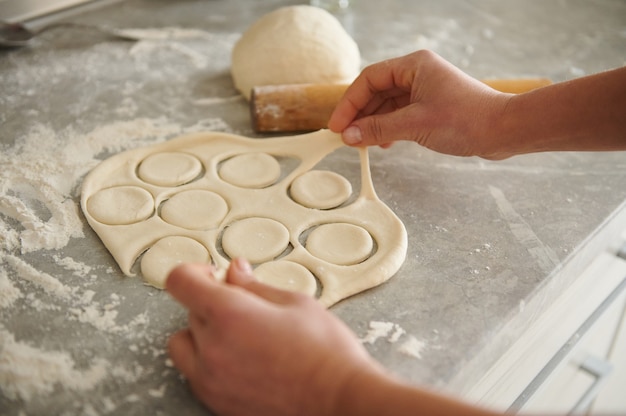 Ciasto na pierogi i ravioli na kuchennym stole posypanym mąką