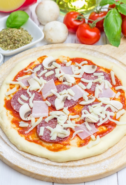 Ciasto na pizzę z sosem pomidorowym, salami, boczkiem, pieczarkami i serem