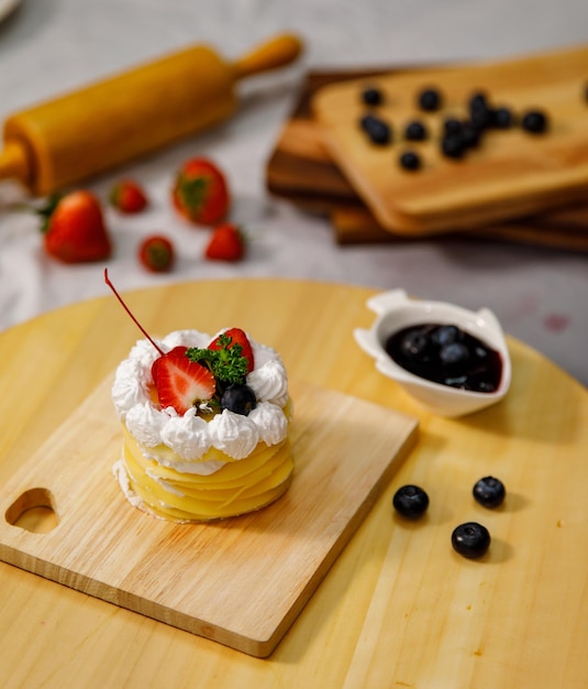 Ciasto naleśnikowe z sosem truskawkowym pyszne udekorowane świeżymi truskawkami na drewnianym talerzu, na urodziny, walentynki i uroczystości