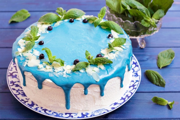 Ciasto ozdobione niebieską śmietaną, miętą i jagodami.