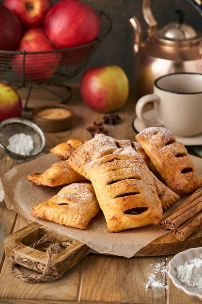 Ciasto ręczne Mini ciasto francuskie lub ciasta ręczne nadziewane jabłkiem i posypane cukrem pudrem w drewnianym talerzu Domowa przekąska z ciasta ze skórką na śniadanie rustykalne zdjęcie Kopiuj miejsce