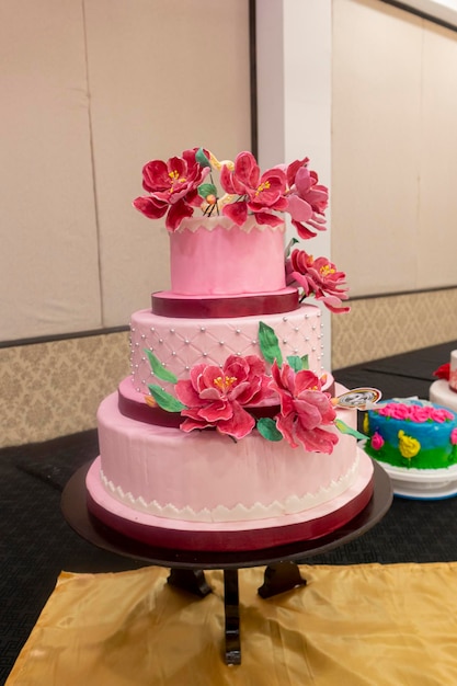 Ciasto ślubne ozdobione kwiatami i wstążkami na stole