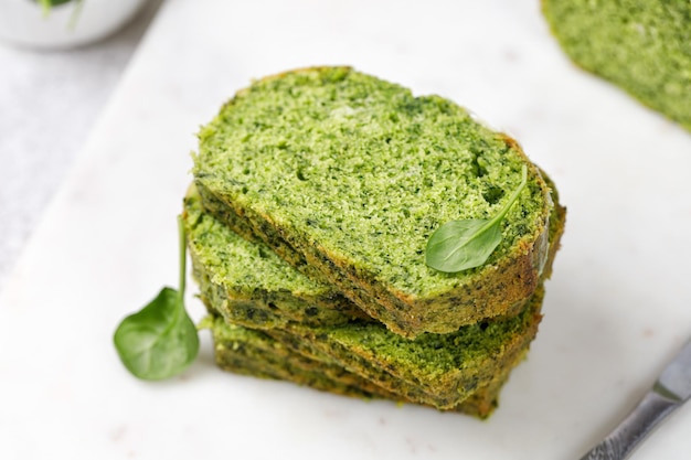 Ciasto szpinakowe z płatkami migdałowymi pokrojonymi na desce Kawałki zielonego ciasta biszkoptowego Tekstura zielonego ciasta