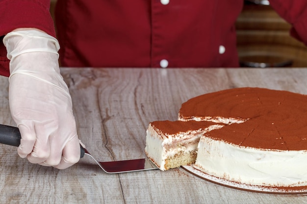 Zdjęcie ciasto tiramisu z krojeniem z plasterkiem i ostrzem na szarym tle zbliżenia