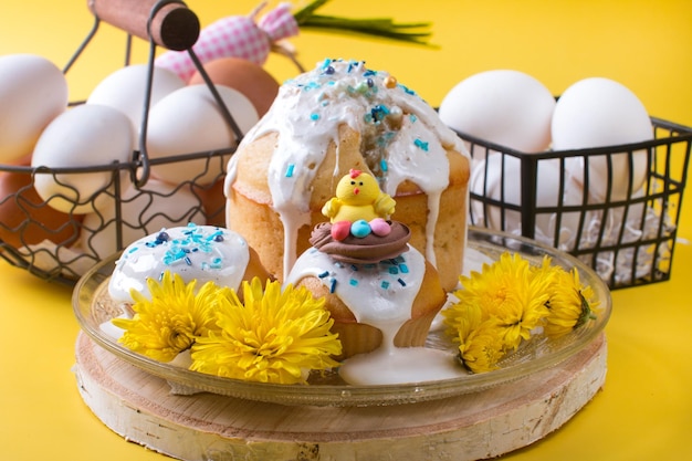 Ciasto wielkanocne i jaja z kwiatami na żółtym tle Koncepcja strony wielkanocnej