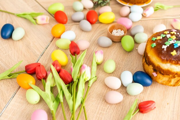 Ciasto wielkanocne i kolorowe jajka i kwiaty na pierwszym planie.