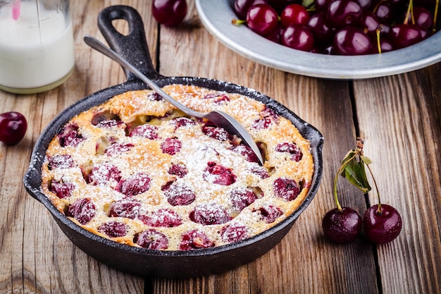 Ciasto wiśniowe Clafoutis na rustykalnym drewnianym tle