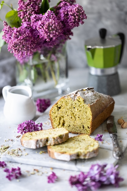 Ciasto z pistacjami i szpinakiem z filiżanką kawy z bukietem bzu na stole. kopia przestrzeń