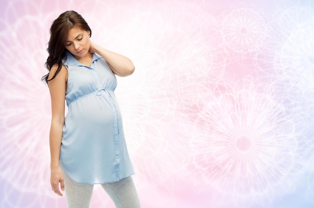 ciąża, zdrowie, ludzie i koncepcja oczekiwań - kobieta w ciąży w łóżku dotykająca pleców i cierpiąca na ból karku na różowym tle kwarcu i spokoju