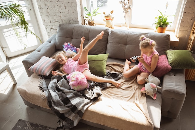 Zdjęcie ciche małe dziewczynki bawiące się w sypialni w uroczej piżamie, domowym stylu i wygodzie