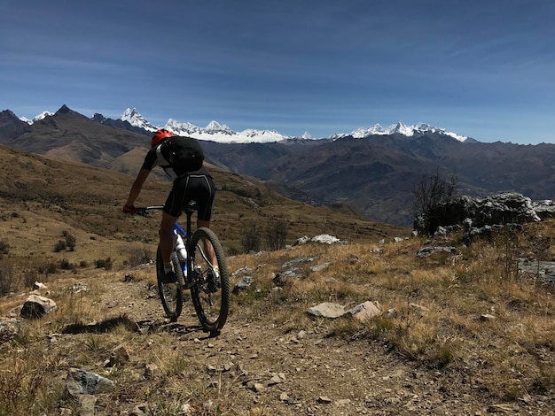 Ciclista de espalda alejandose cuesta abajo por un camino