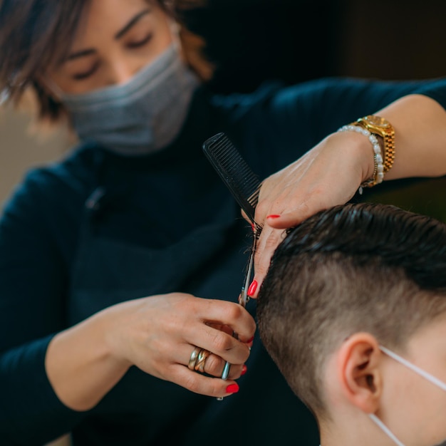 Cięcie włosów chłopca w salonie piękności noszenie maski ochronnej zbliżenie