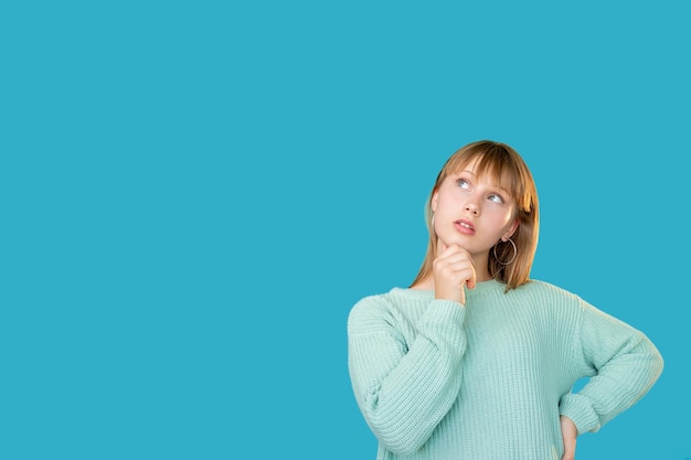 Ciekawa kobieta Tło reklamy Rozwiązanie problemu Trudny wybór Portret wątpliwej zdezorientowanej kobiety w myśleniu sweter, biorąc pod uwagę niewidzialną opcję patrząc na miejsce na kopię odizolowaną na niebiesko