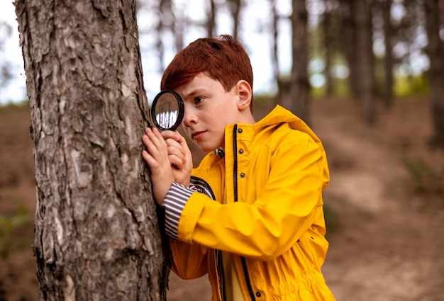 Zdjęcie ciekawy chłopiec z lupą w lesie