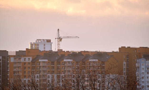 Ciemna sylwetka żurawi wieżowych na budowie wysokich budynków mieszkalnych o zachodzie słońca