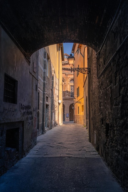 Ciemna wąska pusta stara średniowieczna ulica z kolorowymi budynkami w miejscach światła słonecznego Florencja Włochy