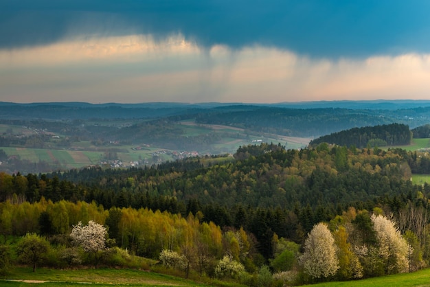 Ciemne chmury nad zielonymi, bujnymi wzgórzami na polskiej wsi