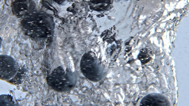 Ciemne jagody podrzucające wir wody szkło zbliżenie Detox płyn wirujący