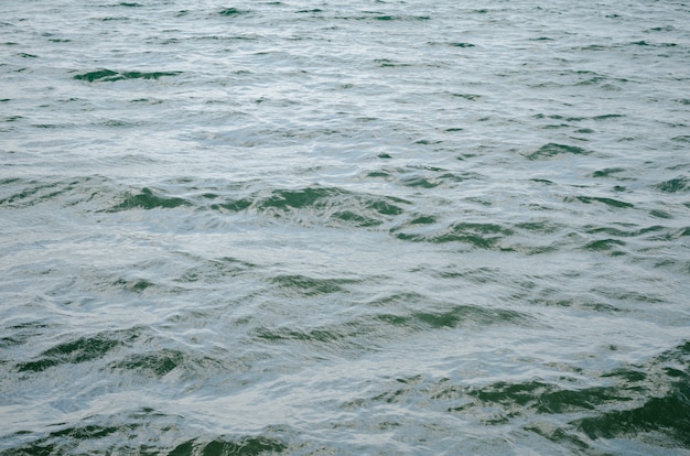 Ciemnoniebieskie tło powierzchni wody. Tekstura powierzchni wody oceanu. Fale głębinowe