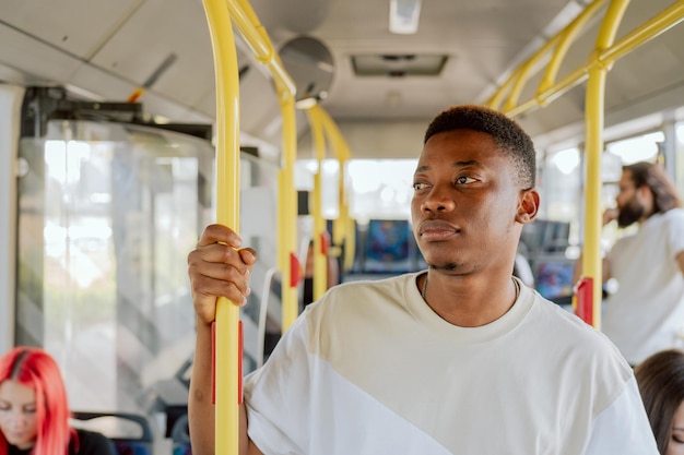 Ciemnoskóry mężczyzna stoi w środku autobusu jadącego z domu do pracy