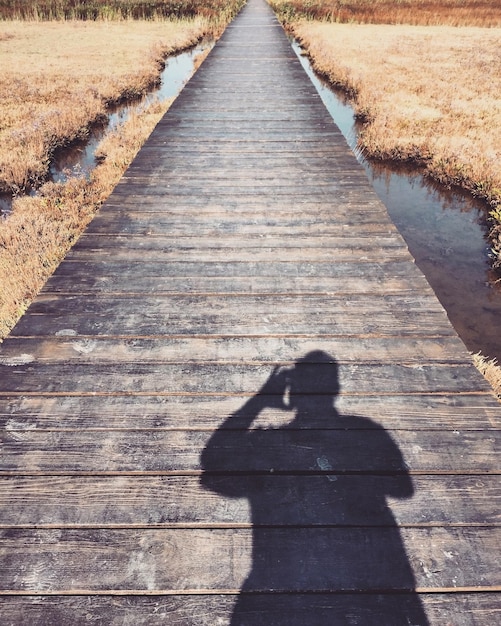 Cień człowieka na promenadzie pośród pola