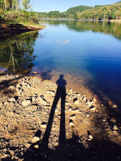 Zdjęcie cień człowieka na skale przy jeziorze