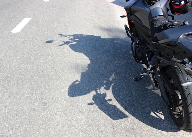Cień motocykla stojącego na poboczu autostrady w słoneczny dzień.