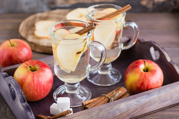Ciepła kojąca herbata z jabłek i cynamonu w szklankach i składnikach do gotowania na drewnianym stole. Koncepcja Detox, antydepresant