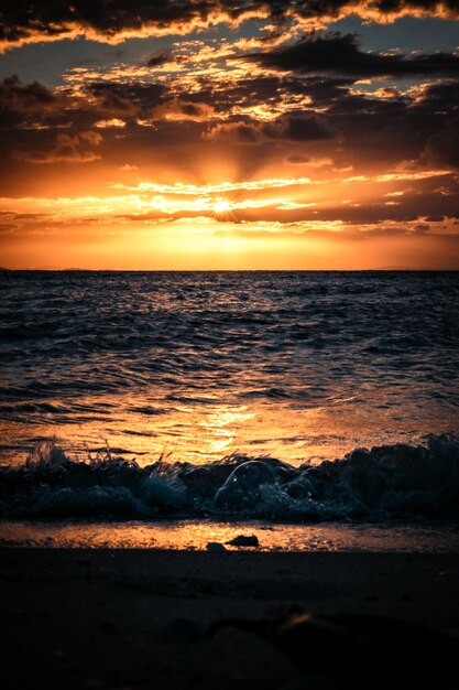 Zdjęcie ciepły zachód słońca widziany z plaży z falami i chmurami