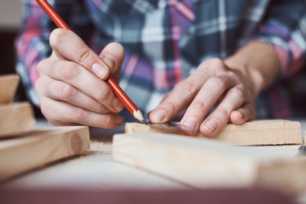 Cieśla ręki bierze pomiar z ołówkiem drewniana deska. Koncepcja stolarki DIY i produkcji mebli